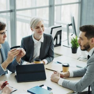 Group of professionals having a discussion in a modern office setting with natural light.